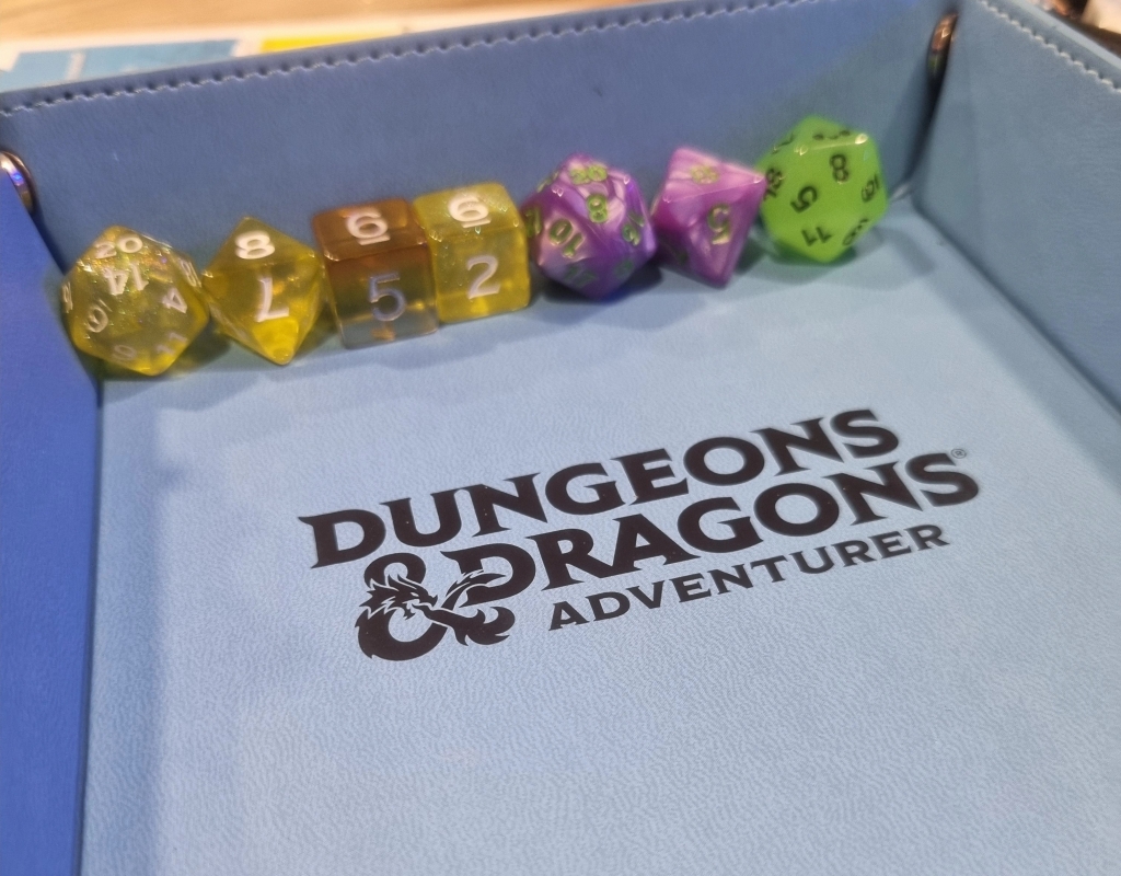 Some dice - an assortment of d20s, d8s, and d6s, resting in a blue dice tray with the Dungeons and Dragons embossed on it in black
